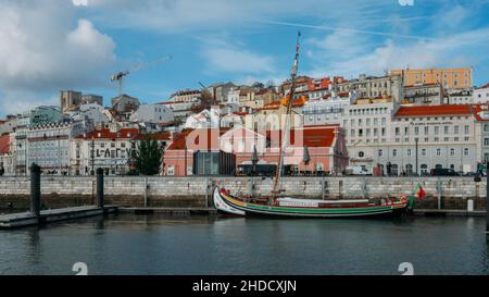 Lissabon, Portugal - 5. Januar 2022: Traditionelle Holzboote werden an einem Wintertag im Yachthafen von Lissabon mit Blick auf die hügelige Stadtlandschaft von Li festgemacht Stockfoto