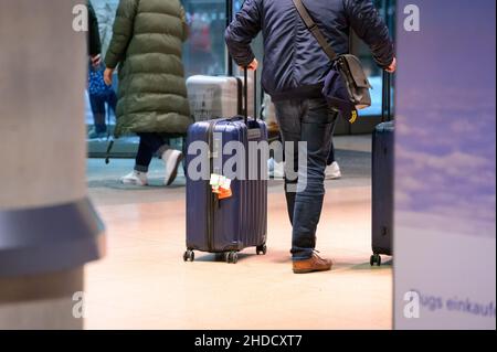 Hamburg, Deutschland. 04th Januar 2022. Rückkehrpassagiere des Kreuzfahrtschiffs 'AIDAnova' laufen in der Nacht mit ihren Koffern durch den Ankunftsbereich des Hamburger Flughafens, nachdem sie in einem von zwei Charterflügen nach Deutschland zurückgeflogen wurden. Aida Cruises hatte beschlossen, die Reise der 'AIDAnova' in Lissabon nach den Infektionsfällen abzubrechen und nicht wie geplant bis Mittwoch in Richtung der Kanarischen Inseln weiterzufahren. Quelle: Jonas Walzberg/dpa/Alamy Live News Stockfoto