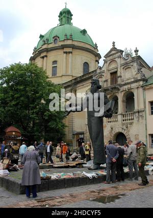 Lviv, Ukraine: Buchmarkt und Flohmarkt auf dem Muzeina-Platz hinter der Dominikanerkirche oder der Kirche der Heiligen Eucharistie. Die Statue ist von Ivan Fedorov. Stockfoto