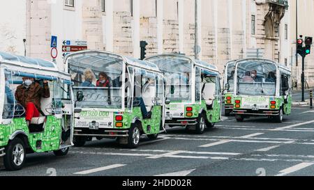 Lissabon, Portugal - 5. Januar 2022: Reihe von Tuk Tuks mit Touristen auf einer Straße in Lissabon, Portugal Stockfoto