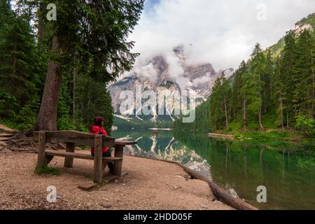 Eine junge Frau in einem gestreiften Hemd hält ihren Hut in den Bergen nahe dem Lago di Prags in Italien Stockfoto