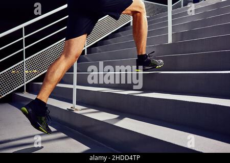 Athletischer Mann, der die Treppe hochläuft. Jogger arbeitet Stockfoto