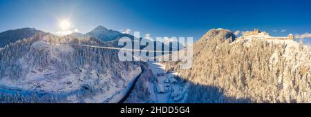 Fußgängerhängebrücke über Einsiedelei und Ruine ehrenberg in reutte im schneebedeckten Winter mit Sonnenstrahlen Stockfoto