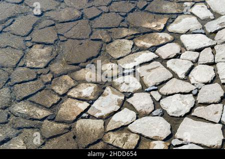 Textur, die durch die feuchten Felsen des Flussbetts hergestellt wird Stockfoto
