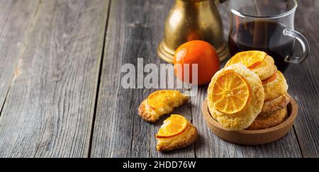 Hausgemachte Kekse mit in Scheiben geschnittenen Mandarinen und Weihnachtsspielzeug in einer dunklen Box. Selektiver Fokus. Stockfoto