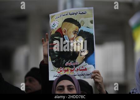 Nablus, Palästina. 05th Januar 2022. Der Palästinenser hält ein Plakat des palästinensischen Gefangenen Hisham Abu Hawasch, der sich 141 Tage lang in israelischen Gefängnissen im Hungerstreik befindet. Kredit: SOPA Images Limited/Alamy Live Nachrichten Stockfoto