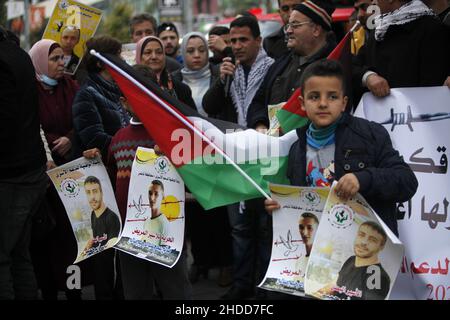 Nablus, Palästina. 05th Januar 2022. Der Palästinenser hält ein Plakat des palästinensischen Gefangenen Hisham Abu Hawasch, der sich 141 Tage lang in israelischen Gefängnissen im Hungerstreik befindet. (Foto von Nasser Ishtayeh/SOPA Images/Sipa USA) Quelle: SIPA USA/Alamy Live News Stockfoto