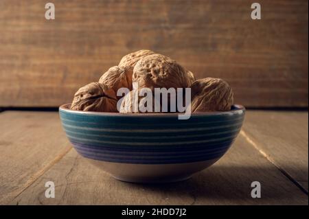 Walnüsse in einer Keramikschale auf dunklem Holzhintergrund Stockfoto