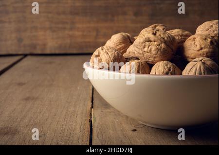 Walnüsse in einer Keramikschale auf dunklem Holzhintergrund Stockfoto