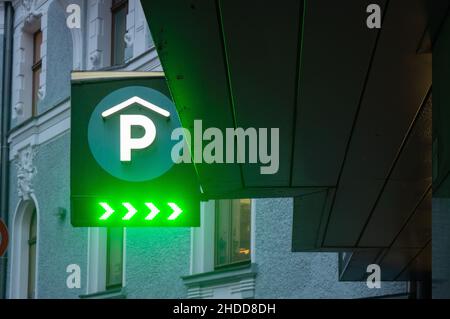 Riga, Lettland, 4. Januar 2022: Stadtansicht des Parkplatzes mit P und Neonlicht-Richtungsschild Stockfoto