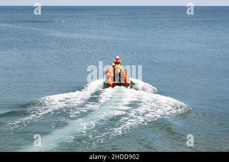 Ein aufblasbares Küstenrettungsboot, das vom Strand in Sidmouth Devon, England, zu einer Rettungsmission aufbricht. Besetzt mit zwei Besatzungen, die auf dem Weg auf See sind Stockfoto