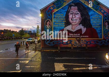 Kinder, die das Wandbild von Bobby Sands in Belfast, Nordirland, passieren, er ist das Symbol des Krieges zwischen katholiken und Protestanten Stockfoto