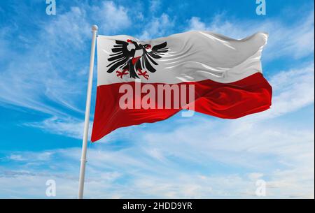 Flagge der Hansestadt Lübeck bei bewölktem Himmel bei Sonnenuntergang, Panoramablick. Bundesrepublik Deutschland. Platz zum Kopieren für breites Banner. 3D Abbildung Stockfoto