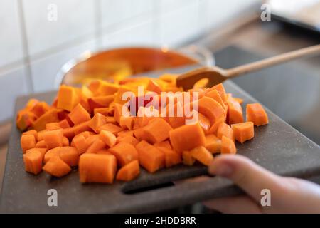 Kürbiswürfel auf Schneidebrett Stockfoto