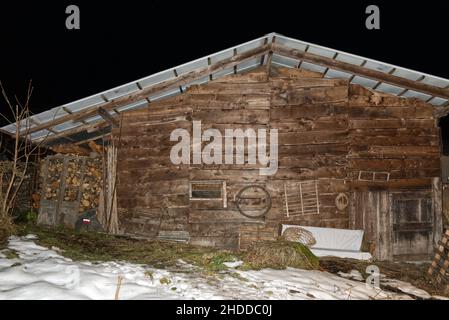 Holzwand einer alten Almhütte im Schnee Stockfoto