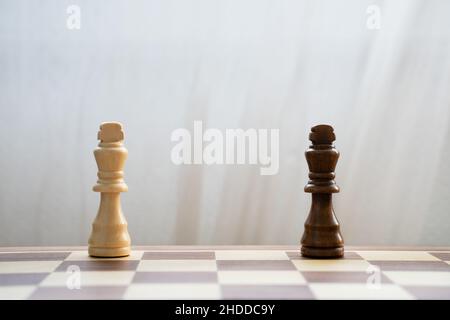 Schwarz-weiße Könige zerteilen sich auf einem hölzernen Schachbrett auf hellem Hintergrund. Interrassische Beziehungen und multiethnische Diversity Support-Konzept Stockfoto