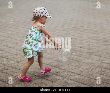 Hübsches kleines Mädchen spielt mit großen Blasen in der Straße am Sommertag, Spanien Stockfoto