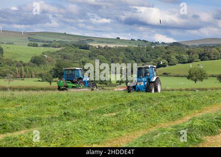 1988 Ford 7610 Force Two mit Kuhn FC243 Mäher, 1993 Ford 8630 mit John Deere 331 Mäher Arbeiten in der englischen Landschaft Schneiden Silage Stockfoto