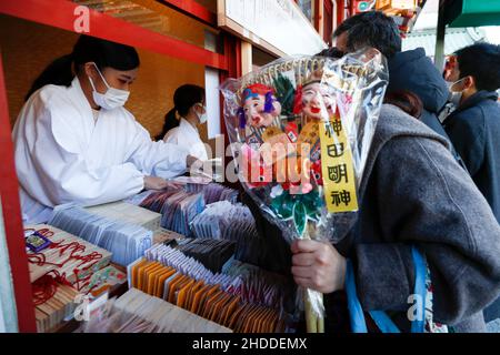 Tokio, Japan. 5th Januar 2022. Mitarbeiter, die eine schützende Gesichtsmaske tragen, verkaufen Glücksbringer im Kanda Myojin-Schrein. Viele Unternehmen schicken am 4. Und 5. Januar, den ersten Arbeitstagen des Jahres, Arbeiter in den Schrein, um für das Glück im Geschäft zu beten. (Bild: © Rodrigo Reyes Marin/ZUMA Press Wire) Stockfoto