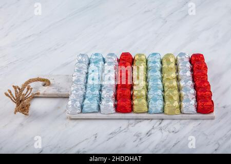 Runde Schokoladenkugeln mit Aluminiumfolie in Box-Behälter auf Marmorboden. Minimalistische, festliche Frühlingskomposition. Weicher selektiver Fokus, Stockfoto