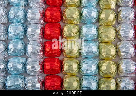 Runde Schokoladenkugeln mit Aluminiumfolie in Box-Behälter auf Marmorboden. Minimalistische, festliche Frühlingskomposition. Weicher selektiver Fokus, Stockfoto