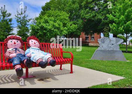 Arcola, Illinois, USA. Große Raggedy Ann und Raggedy Andy Puppen schmücken eine Bank in der Nähe des alten Eisenbahndepot in Arcola, Illinois. Stockfoto