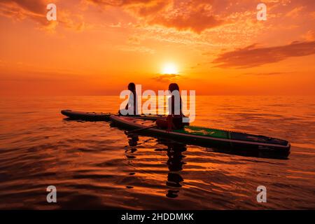 25. Juni 2021. Anapa, Russland. Reisende auf Stand Up Paddle Board an ruhigen Meer mit Sonnenuntergang oder Sonnenaufgang. Mädchen auf Red Paddle Suppboard und Sonnenuntergang mit re Stockfoto