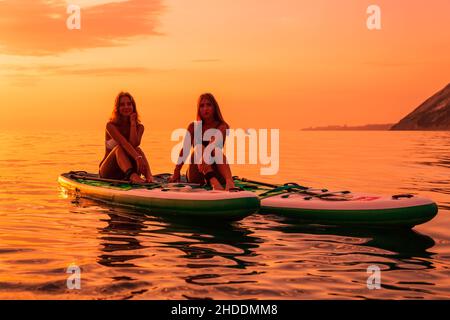 25. Juni 2021. Anapa, Russland. Reisende auf Stand Up Paddle Board an ruhigen Meer mit Sonnenuntergang oder Sonnenaufgang. Mädchen auf Red Paddle Suppboard und Sonnenuntergang mit re Stockfoto