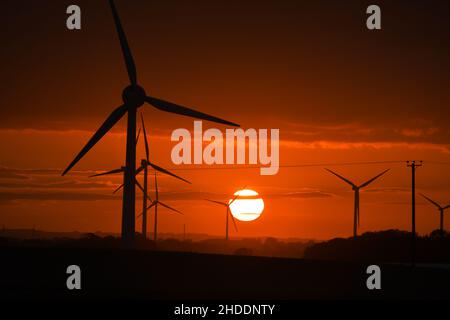 Dramatischer Sonnenuntergang hinter riesigen Windturbinen Stockfoto