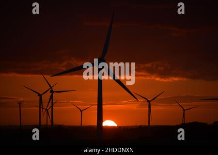 Dramatischer Sonnenuntergang hinter riesigen Windturbinen Stockfoto