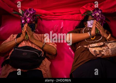 Bangkok, Thailand. 31st Dez 2021. Thailändische Frauen legen sich nieder und beten in einem Sarg während des Auferstehungsrituals im Tempel.Devotees werden in einem jährlichen Neujahrsritual im Wat Takien in der Nähe von Nonthaburi wiederbelebt. Dieser Ritus beginnt mit einem Gebet, gefolgt von den Teilnehmern, die mit heiligen Fäden um ihren Kopf gewickelt singen, bevor sie sich in einen Sarg legen, um zu „sterben“ und gereinigt zu werden. Kredit: SOPA Images Limited/Alamy Live Nachrichten Stockfoto