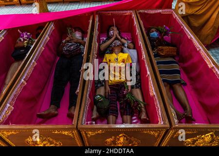 Bangkok, Thailand. 31st Dez 2021. Die thailändische Familie wird gesehen, wie sie in Särgen als Teil des Auferstehungsrituals im Tempel lag.Devotees werden in einem jährlichen Neujahrsritual im Wat Takien in der Nähe von Nonthaburi wiederauferstehen. Dieser Ritus beginnt mit einem Gebet, gefolgt von den Teilnehmern, die mit heiligen Fäden um ihren Kopf gewickelt singen, bevor sie sich in einen Sarg legen, um zu „sterben“ und gereinigt zu werden. (Foto von Matt Hunt/SOPA Images/Sipa USA) Quelle: SIPA USA/Alamy Live News Stockfoto