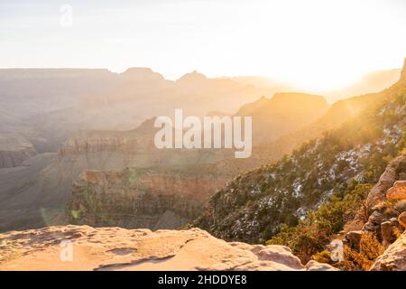 Über dem Rand des Grand Canyon steigt die Sonne auf und sendet am Wintermorgen Lichtwellen tief in den Canyon Stockfoto