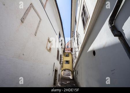Bild einer typischen Straße aus dem Stadtzentrum von Skofja Loka, Slowenien, in der Nähe der Katstle, mit einem schmalen alten Haus über einer Straße. Skofja Loka ist eine Stadt Stockfoto