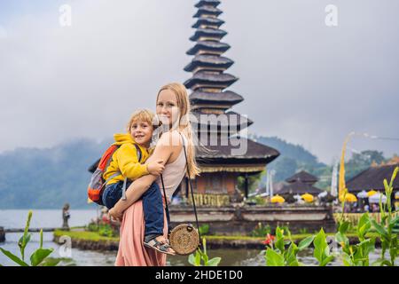 Mutter und Sohn im Hintergrund von Pura Ulun Danu Bratan, Bali. Hindu Tempel umgeben von Blumen auf Bratan See, Bali. Große Shivaite wasser Tempel in Stockfoto