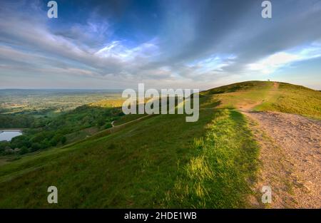 Die Sommersonne geht über die Landschaft von Worcestershire auf, strahlt tiefes, schräges Sonnenlicht über einen steinigen Wanderweg, der über die Gipfel führt, umgeben Stockfoto