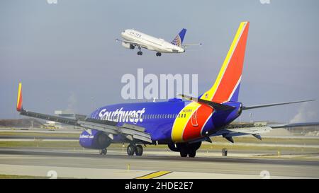 Southwest Airlines Boeing 737 Taxis auf der Start- und Landebahn nach der Landung am Chicago O'Hare International Airport, während ein United-Flugzeug in der Ferne abhebt. Stockfoto