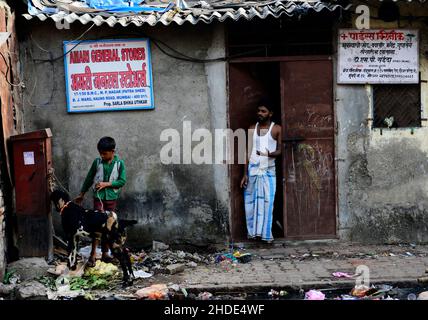 Ein indischer Junge, der seine Ziege im Geschäft seines Vaters in Mumbai, Indien, hält. Stockfoto