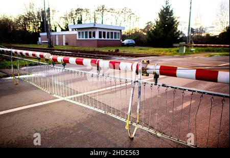 Ihrhove, Deutschland. 15th Dez 2021. Die Schranke an einem Bahnübergang auf der zweigleisigen Bahnstrecke bei Ihrhove wird vor der Durchfahrt eines Zuges gesperrt. Der so genannte "Westline" wird künftig Norddeutschland über die Strecke Bremen-Groningen mit dem Norden der Niederlande verbinden. Die Strecke wird aufgerüstet, um eine schnellere, komfortablere und umweltfreundlichere Verbindung zwischen den Metropolregionen zu ermöglichen. Quelle: Hauke-Christian Dittrich/dpa/Alamy Live News Stockfoto