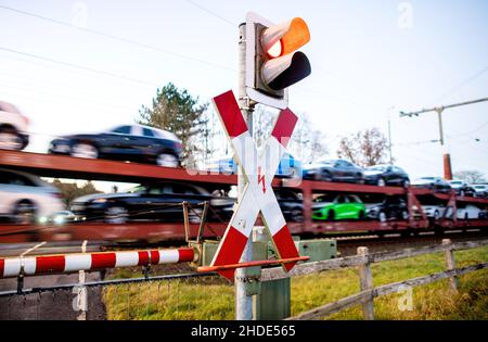 Ihrhove, Deutschland. 15th Dez 2021. Ein Güterzug, der neue Autos befördert, passiert einen Bahnübergang auf der zweigleisigen Eisenbahnlinie in der Nähe von Ihrhove. Der so genannte "Westline" wird künftig Norddeutschland über die Strecke Bremen-Groningen mit dem Norden der Niederlande verbinden. Die Strecke wird aufgerüstet, um eine schnellere, komfortablere und umweltfreundlichere Verbindung zwischen den Metropolregionen zu ermöglichen. Quelle: Hauke-Christian Dittrich/dpa/Alamy Live News Stockfoto