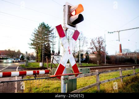 Ihrhove, Deutschland. 15th Dez 2021. Eine Ampel an einem Bahnübergang auf der zweigleisigen Bahnlinie bei Ihrhove leuchtet rot, bevor ein Zug vorbeifährt. Der so genannte "Westline" wird künftig Norddeutschland über die Strecke Bremen-Groningen mit dem Norden der Niederlande verbinden. Die Strecke wird aufgerüstet, um eine schnellere, komfortablere und umweltfreundlichere Verbindung zwischen den Metropolregionen zu ermöglichen. Quelle: Hauke-Christian Dittrich/dpa/Alamy Live News Stockfoto