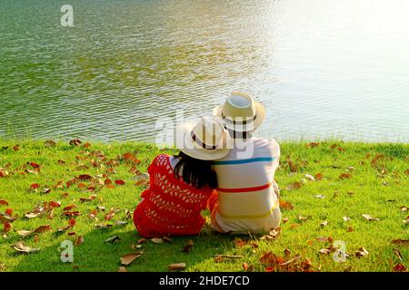 Ein Paar im Strohhut, das sich am See entspannt Stockfoto