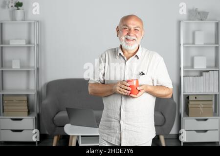 Senior Sozialarbeiter, Psychologe. Großvater, reifer Manager. Alter Mann zu Hause mit Tasse Becher. Stockfoto