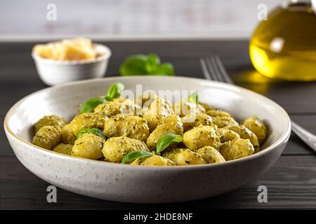 Heiße cremige Kartoffelgnocchi mit Pesto-Sauce, frischem Basilikum und Parmesan. Geringe Tiefenschärfe. Stockfoto