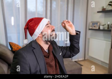 Wir stellen den Teststab in Ihrem Wohnzimmer vor, um zum Weihnachtsessen zu gehen. Mann, der den schnellen Antigen-Test bei sich zu Hause macht, sars-Cov-2, Coronavirus, covid Stockfoto
