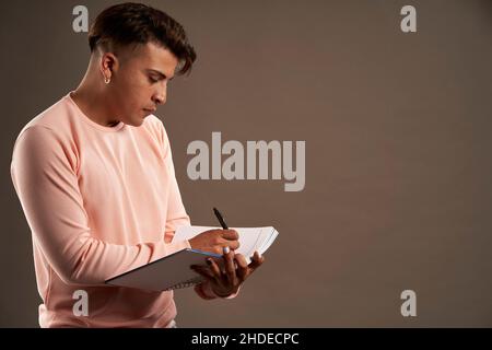 lateinischer Mann, der in einem Notizbuch mit dem Gesicht nach unten steht Stockfoto
