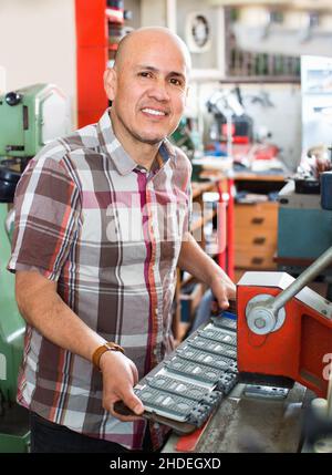 Lächelnder älterer Mann, der Fahrzeugnummern auf der Maschine macht Stockfoto