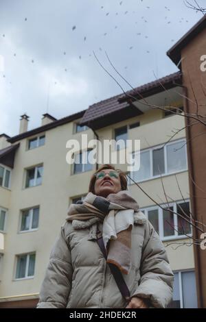Schöne Baby-Boomer-Frau mittleren Alters in einer Brille und stilvoller Freizeitkleidung sieht am Himmel aus. Stockfoto