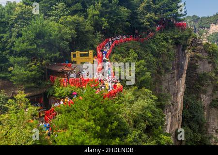 WULINGYUAN, CHINA - 9. AUGUST 2018: Touristen laufen entlang roter Segenbänder, die an Geländern gebunden sind, in dem landschaftlich reizenden und historischen Interessengebiet von Wulingyuan in Zhang Stockfoto