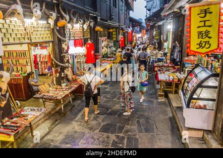 FURONG ZHEN, CHINA - 11. AUGUST 2018: Abendansicht einer engen Gasse mit verschiedenen Ständen in der Stadt Furong Zhen, Provinz Hunan, China Stockfoto